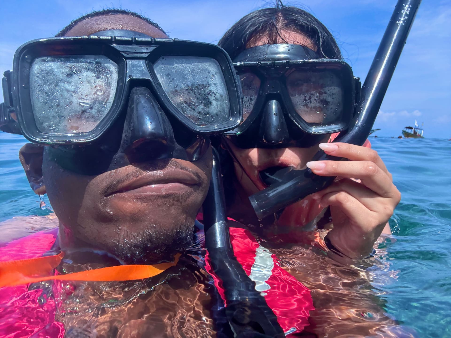Two people in snorkel masks floating in clear blue tropical water